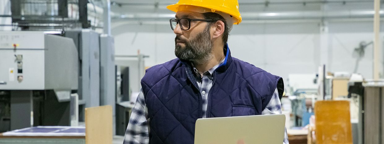 onsite physical therapist with hardhat and laptop